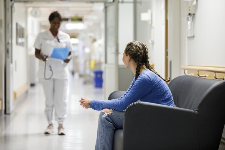 Sköterska hämtar flicka i väntrum på sjukhus